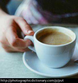 Photo of someone putting down a cup of coffee