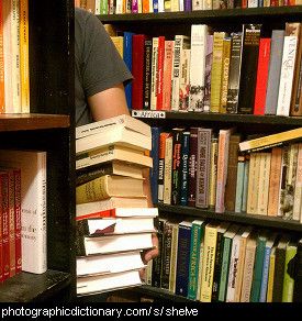 Photo of a man carrying a stack of books